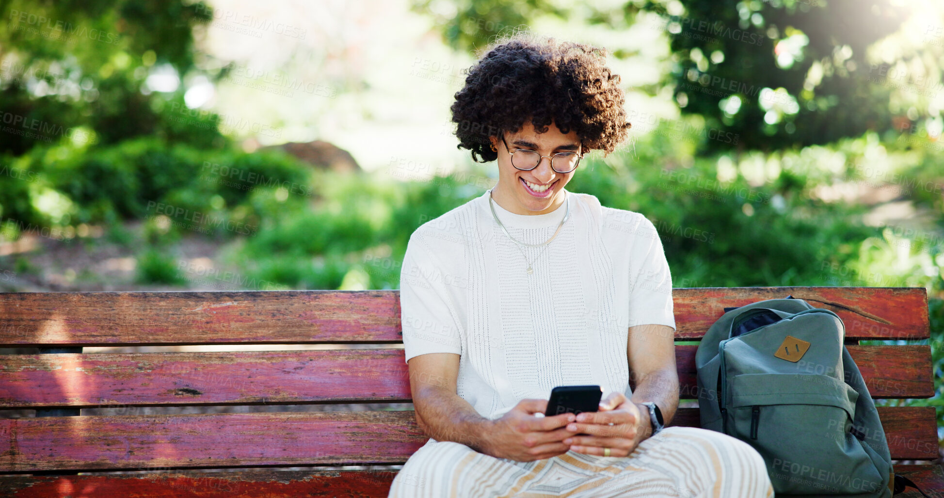 Buy stock photo Man, student and phone with texting on park bench, smile and funny meme on mobile app in summer. Person, smartphone and happy at college with chat, contact and social network at campus in Costa Rica