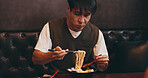 Japanese man, eating lunch and hungry in restaurant for nutrition, culture and healthy meal. Male person, hospitality and diet with traditional cuisine, chopsticks and ramen noodles as asian food