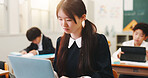 Girl, child and laptop and reading in classroom for study, education and e learning on web with research for project. School, kid and computer for assessment, test and thinking at academy in Japan