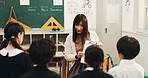 Teacher, children and English learning in classroom for language development, group project and growth. Japanese students, reading together or studying with educator for support, knowledge and help