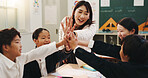 Teacher, students and high five in classroom for language development, group project or collaboration. Japanese children, hands together and study with educator for support, knowledge or growth