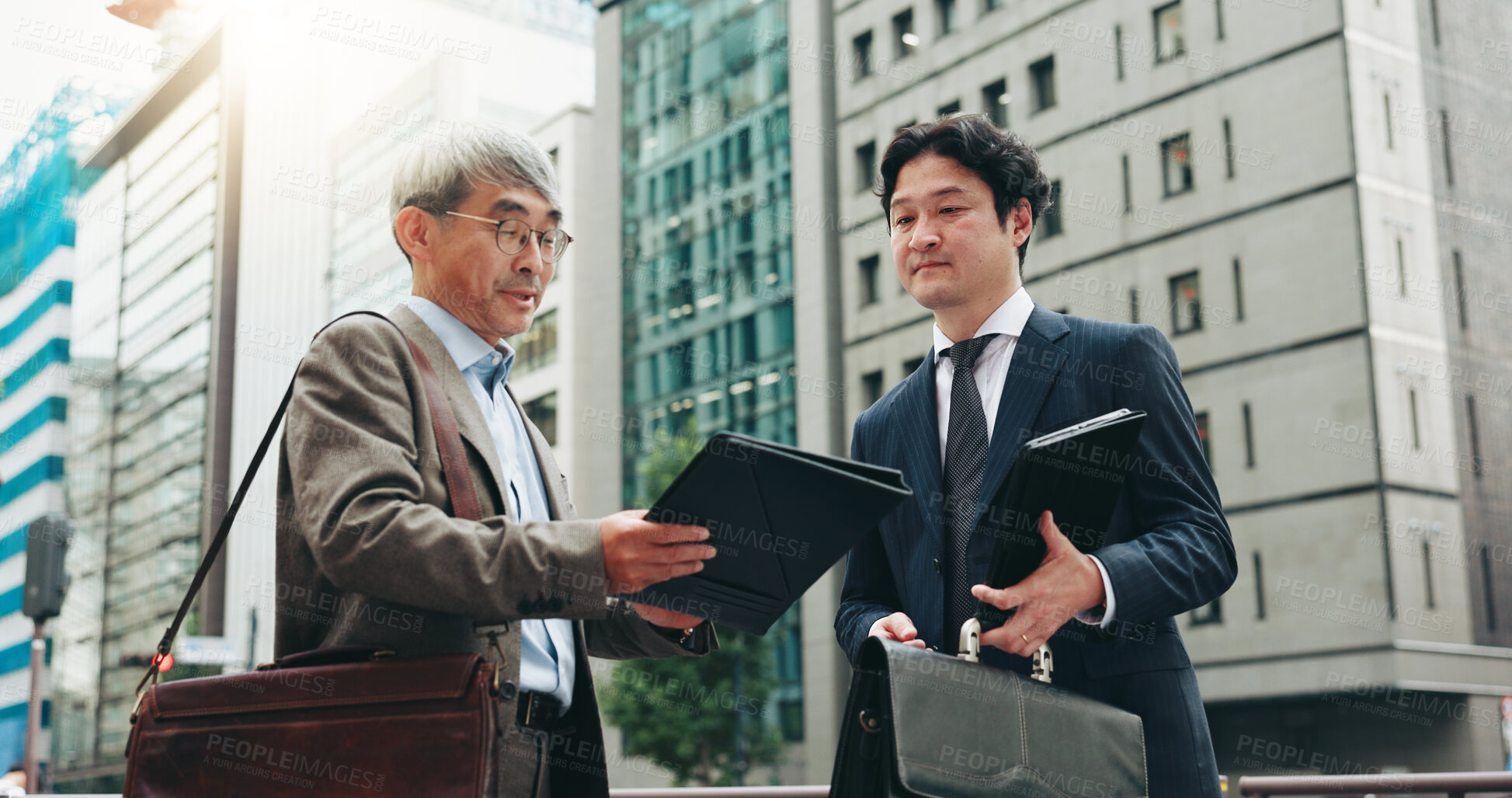 Buy stock photo Outdoor, teamwork and business people in city for documents, development or talking. Urban planner, handover and mature professional Japanese colleagues planning town project file together in Tokyo