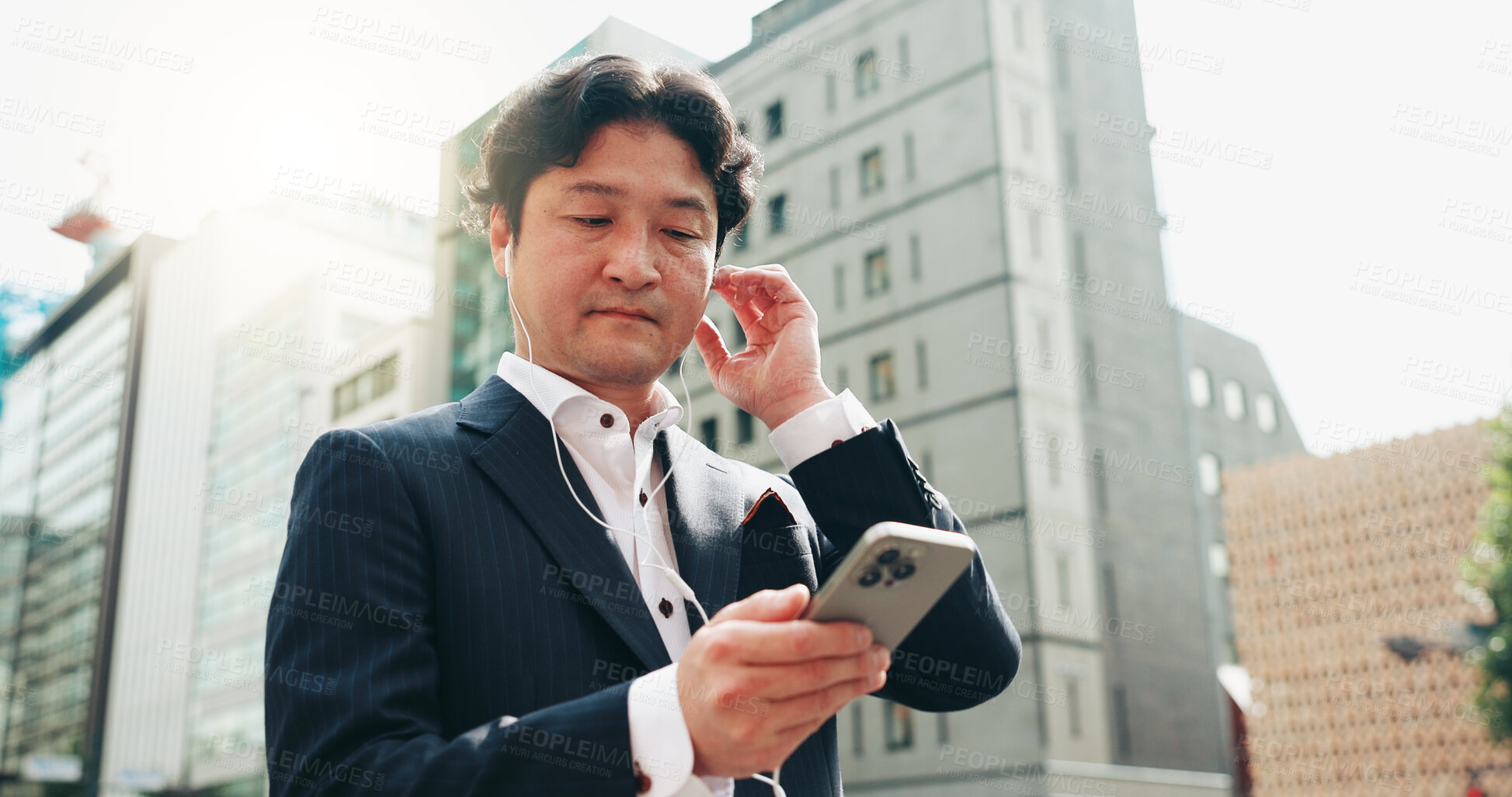 Buy stock photo Earphones, travel and businessman with smartphone, city and listening to app, commuting and morning. Outdoor, audio and watching news with mobile, real estate agent and Japanese person in Japan