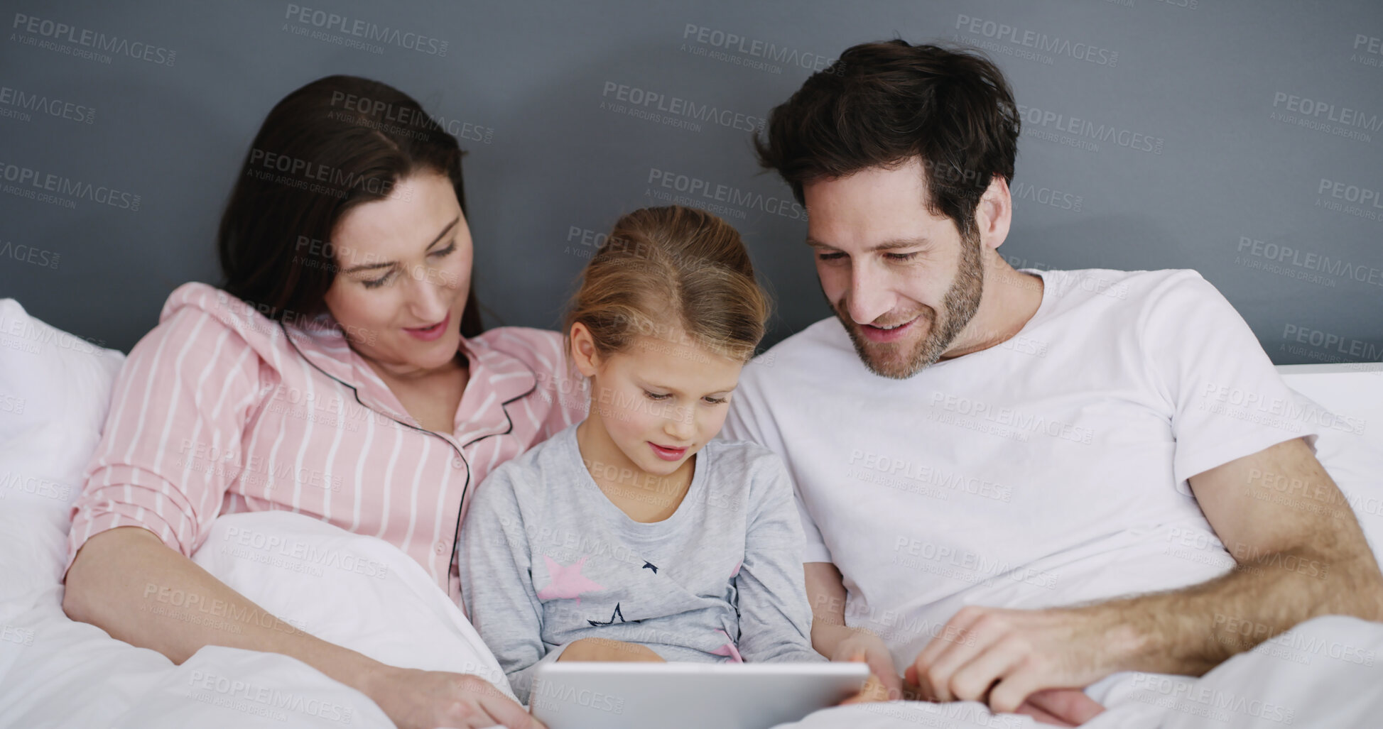 Buy stock photo Relax, tablet and child with parents in bedroom in home for watching show, film or video online. Happy, rest and kid with mom and dad for streaming movie with digital technology in bedroom in house.