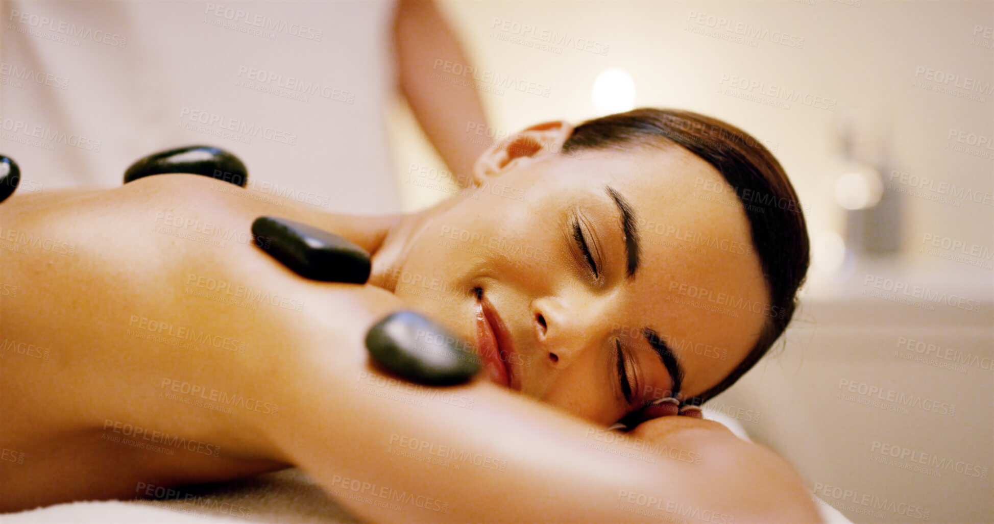 Buy stock photo Woman, rest and massage with hot stones at spa for muscle recovery, natural detox and body treatment. People, masseuse and warm rocks for holistic healing, stress relief and wellness at luxury resort