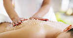 Person, hands and masseuse with salt scrub on back for exfoliation, massage or treatment at spa. Closeup, masseur or client with natural cosmetics for relaxation, detox or physical therapy at salon