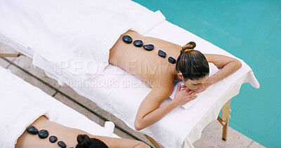 Buy stock photo Women, relax and above with hot rocks at spa for massage, stress relief or release tension. Top view, female people or clients lying on bed with heated stones for detox or physical therapy at salon