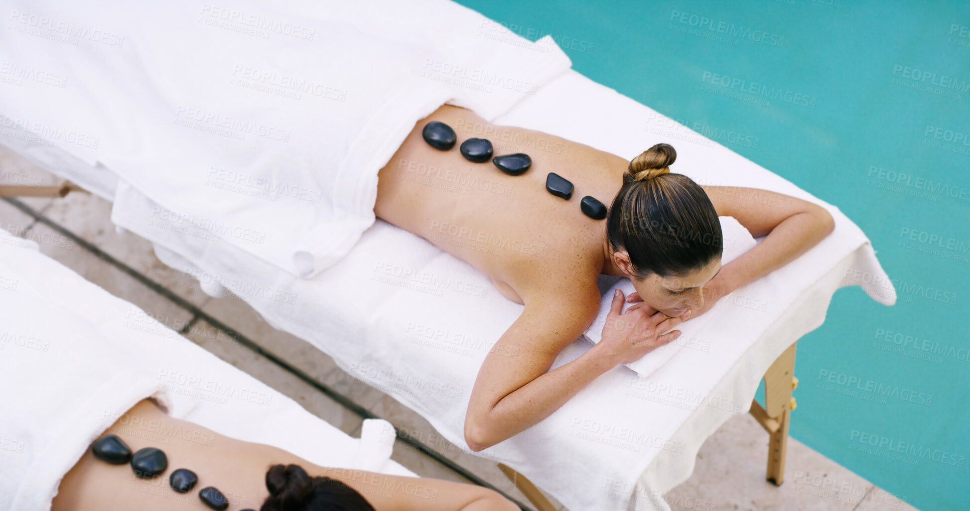 Buy stock photo Women, relax and above with hot rocks at spa for massage, stress relief or release tension. Top view, female people or clients lying on bed with heated stones for detox or physical therapy at salon