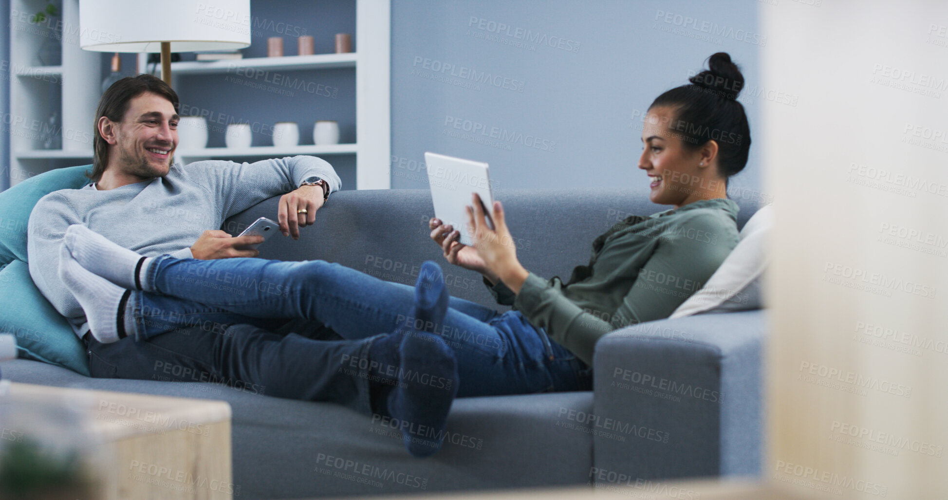 Buy stock photo Man, woman and phone with tablet on sofa, relax and conversation in home, smile and listen in living room. Couple, smartphone and touchscreen with ebook, mobile app or social media ay apartment