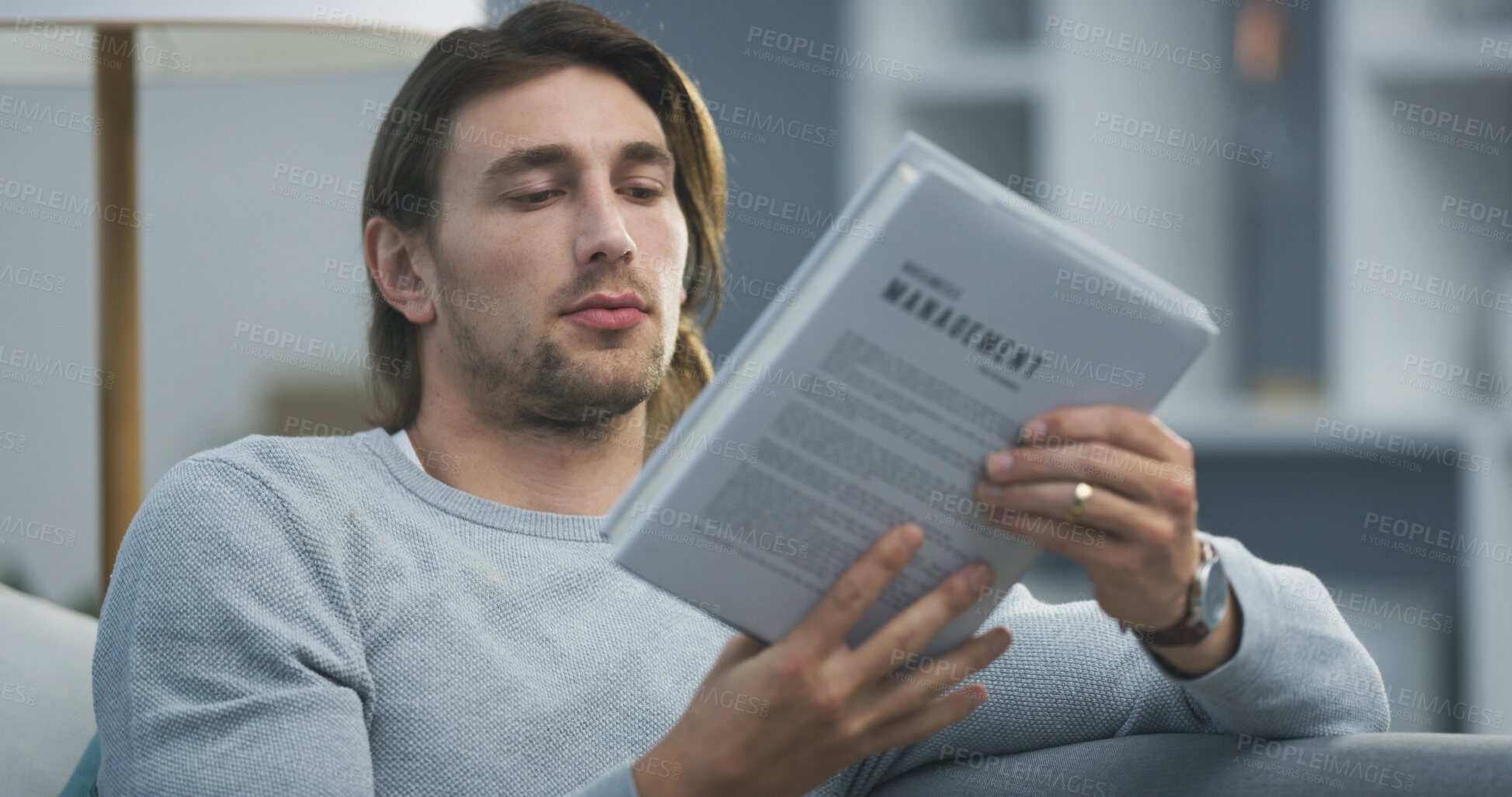 Buy stock photo Man, book and reading on sofa in home, relax and choice for literature on break in living room. Person, novel and check title on couch in lounge with language, storytelling or knowledge at apartment