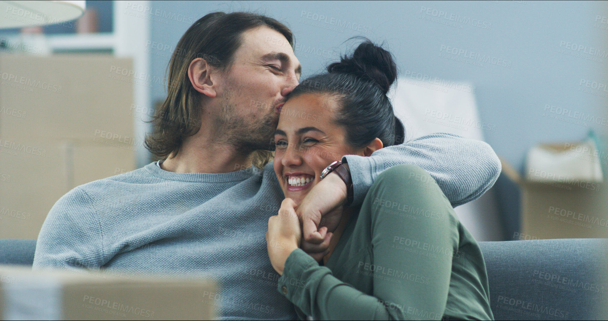 Buy stock photo Happy couple, hug and boxes in new home with kiss, support and pride for investment opportunity. Man, woman and excited on sofa for moving in, relationship milestone and loan approval for apartment