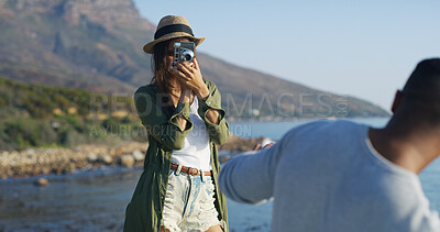 Buy stock photo Ocean, couple and woman with camera for photography, capture memory and bonding with partner outdoor. Relationship, man and photographer with equipment for picture, shooting and adventure on vacation