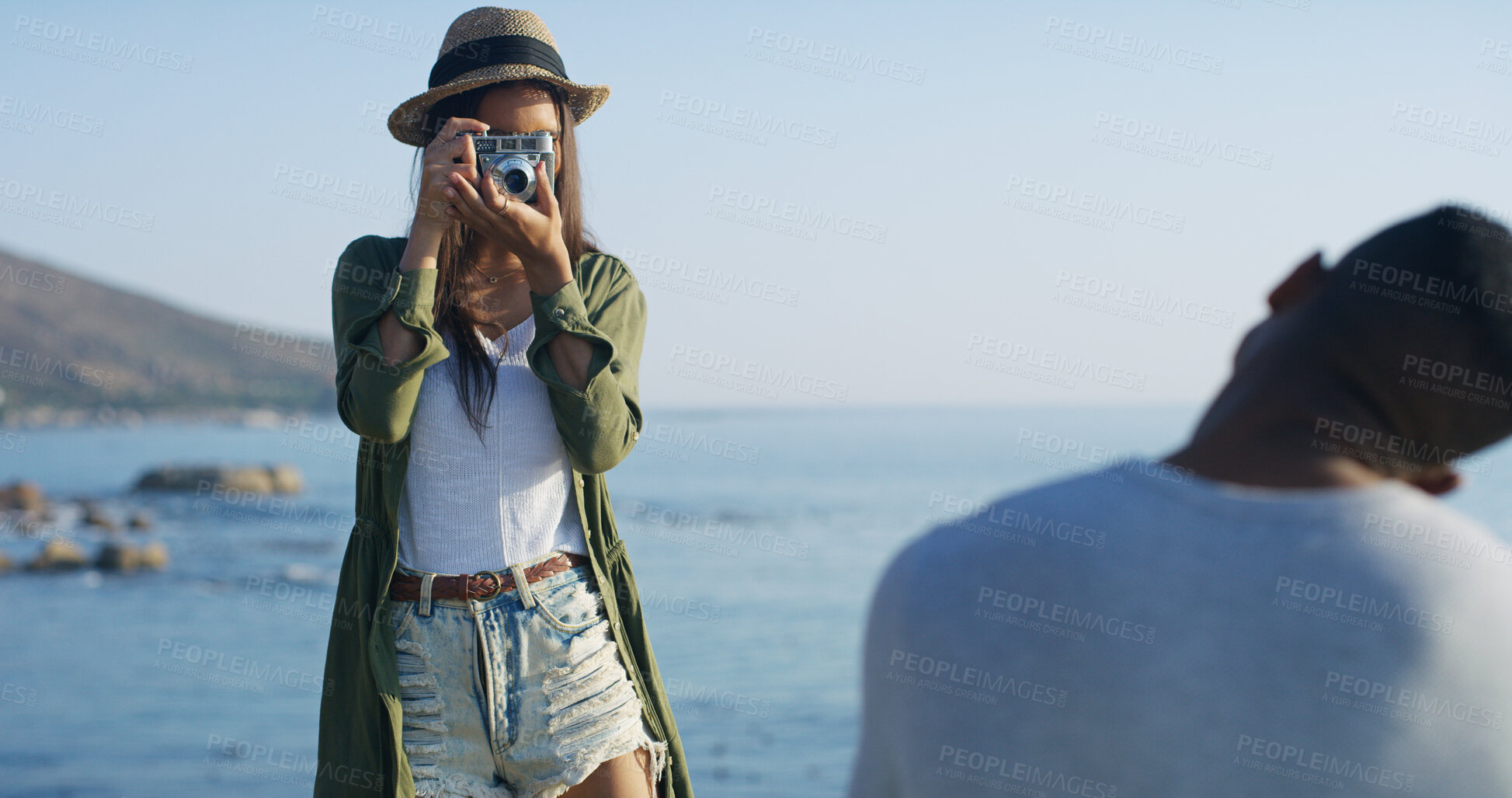 Buy stock photo Ocean, couple and woman with camera for picture, capture memory and bonding with partner outdoor. Relationship, man and photographer with equipment for photography, moment and adventure on vacation