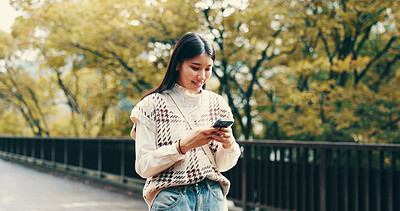 Buy stock photo Japanese woman, walking and phone in street for online networking, dating app and happy with mobile chat. Person, smartphone and smile for social media post, notification or browsing internet in city