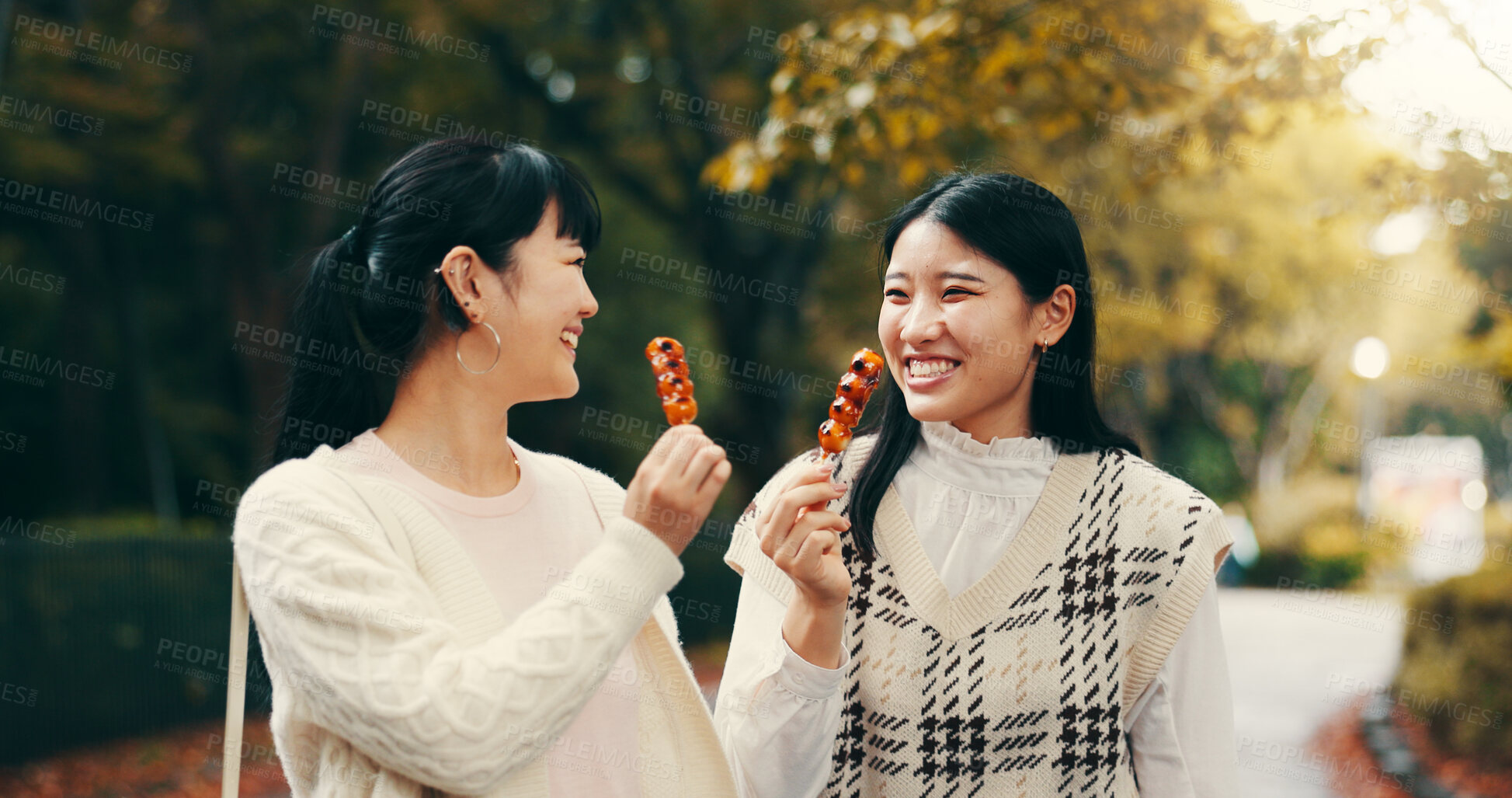 Buy stock photo City, asian women and happy with candy, travel and snack for friends with dango, students and road. Outdoor, commuting and sweets for celebration of reunion, smile and sharing of food in Japan