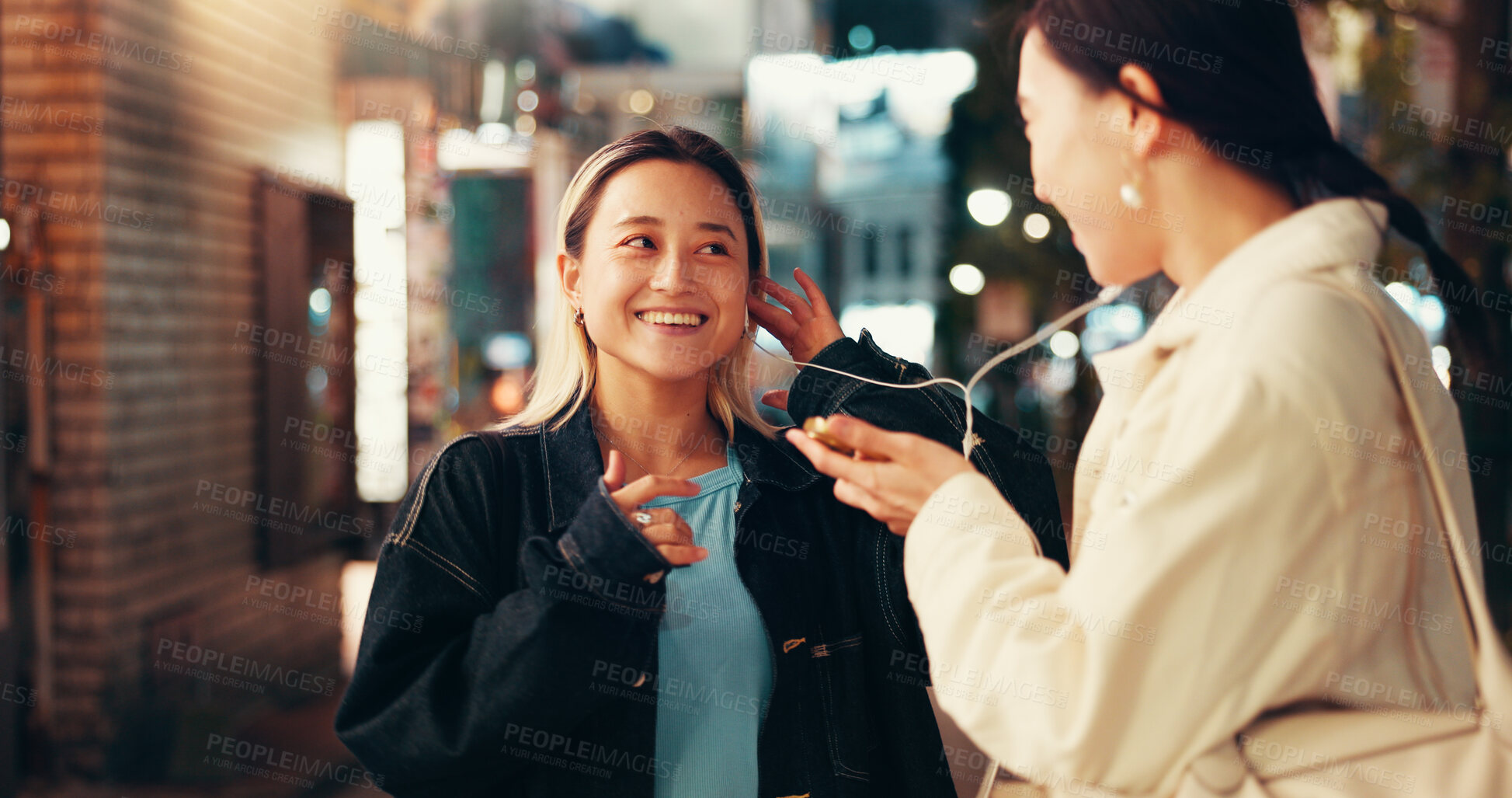 Buy stock photo Earphones, music and share with Japanese people in city for streaming, online playlist and radio. Happiness, bonding and podcast with asian friends listening to audio at night for album and support