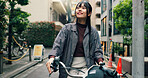 Travel, buildings and Asian woman on bicycle in city for morning commute, adventure or journey outdoors. Location, cycling and person on bike for trip, sustainable and eco friendly transport in Japan