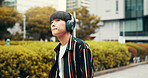 Man, headphones and student travel in city, streaming playlist and online for listening to song. Male person, university campus and hearing sound on journey in Japan, trip and commute to lecture