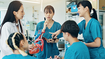 Buy stock photo Professor, students and heart for medical lecture, education or practical assignment in teaching hospital. Healthcare, learn and group with doctor for training on cardiac model at university in Japan