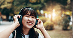 Woman, headphones and worker travel in city, streaming playlist and online for listening. Female person, outdoor employee and hearing sound on journey in Japan, urban town and audio for commute