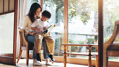 Buy stock photo Reading, study or tablet with mother and son on chair in home for child development or learning. Education, Japanese family or technology with single parent woman and boy in apartment for search