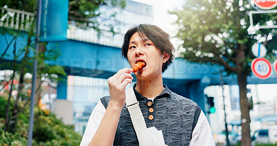 Buy stock photo Asian man, eating and food in city for travel, hungry and traditional snack on afternoon commute in Japan. Student, walk or culture cuisine in Tokyo for lunch, trip or street takeaway of karaage meat