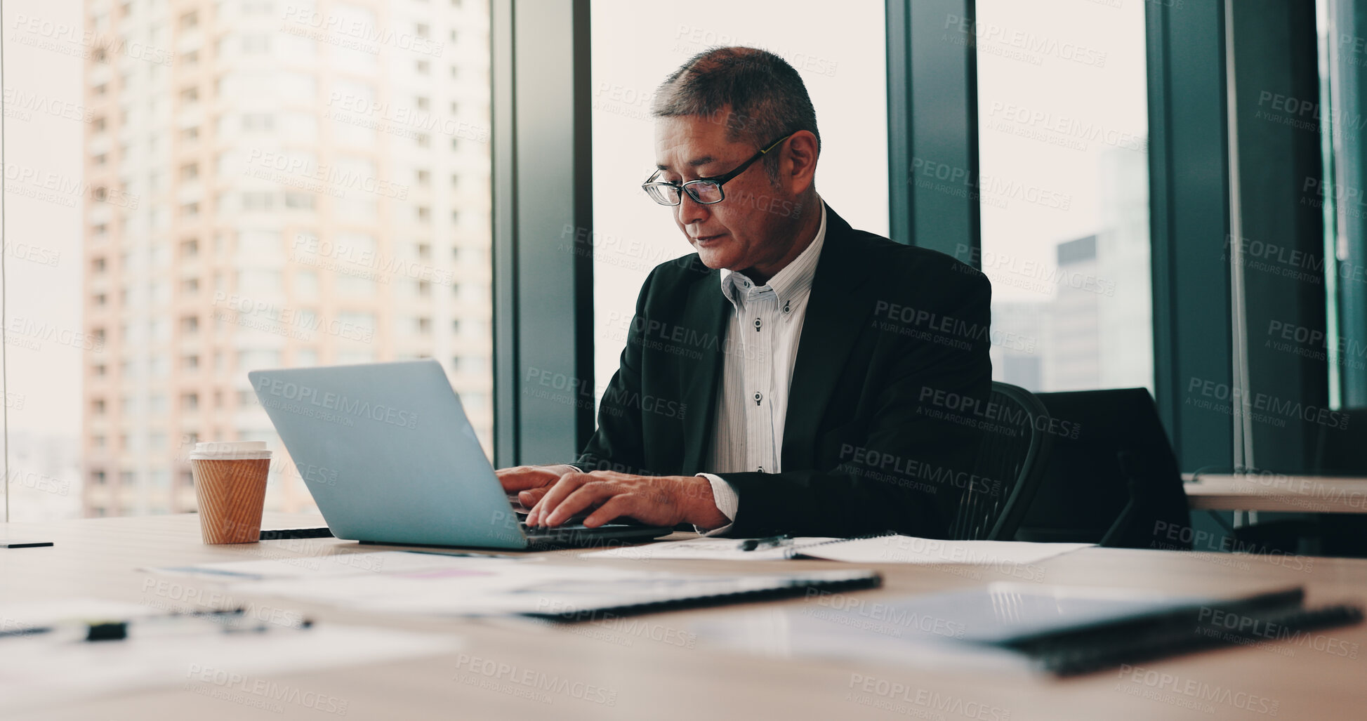 Buy stock photo Office building, Japanese businessman and laptop with typing, documents or project management as ceo. Mature, male person and paperwork on tech for online, connection and review in company or agency