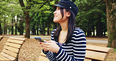 Buy stock photo Bench, phone and thinking with woman in park for adventure, sightseeing or travel to explore Japan. App, idea and social media with smile of happy tourist person outdoor in nature for vacation