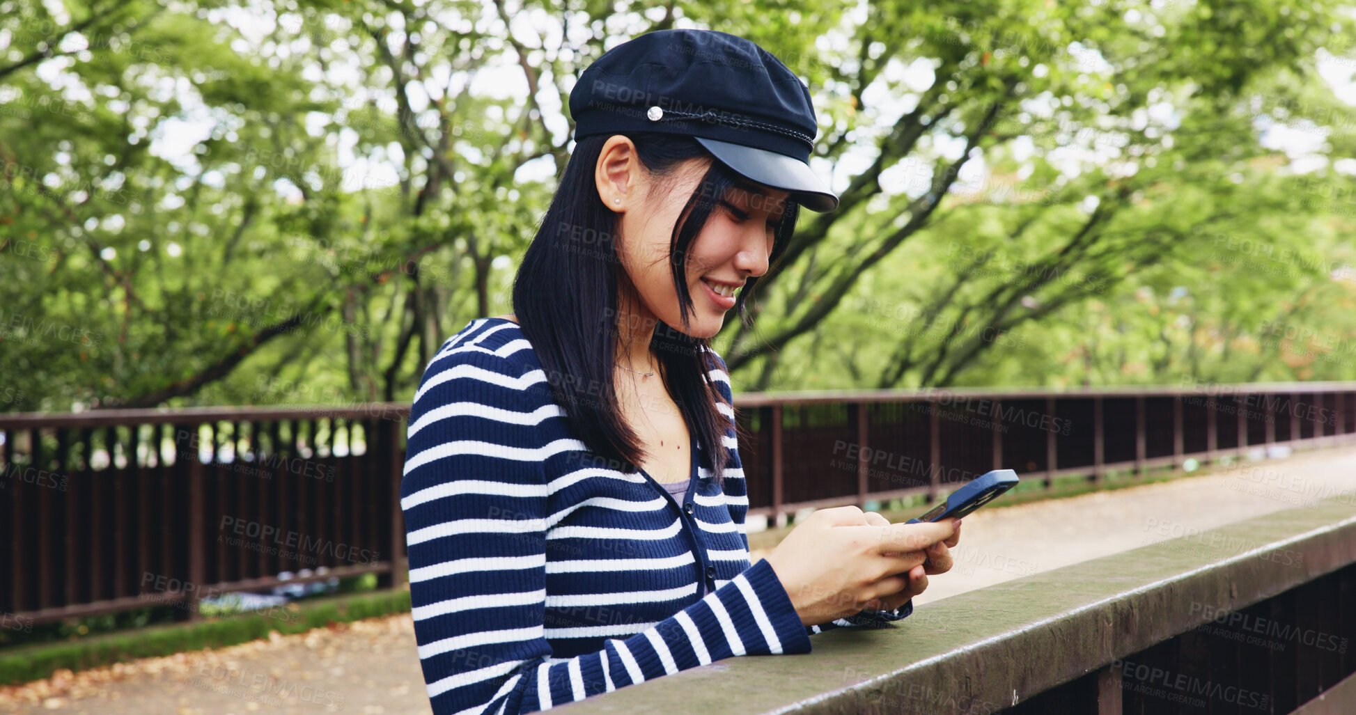 Buy stock photo Bridge, phone and smile with woman in park for adventure, sightseeing or travel to explore Japan. App, relax and social media with happy tourist person outdoor in nature of Tokyo for vacation