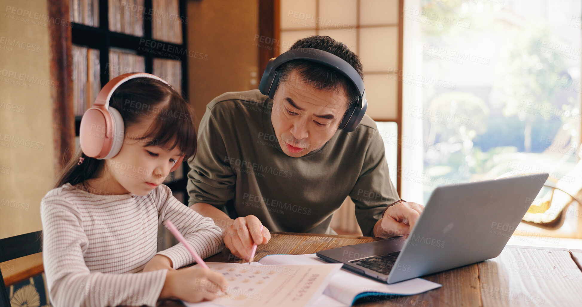 Buy stock photo Asian dad, daughter and headphones with laptop for elearning, language tutoring or teaching at home. Japan, father or child writing with book or computer for online lesson or homeschooling at house