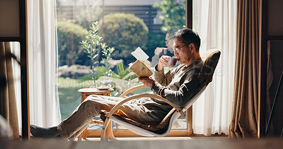 Buy stock photo Asian man, tea and relax with book on chair for reading, story or novel by window at home. Japan, male person or reader with drink, beverage or chapter for fantasy, vocabulary or knowledge at house