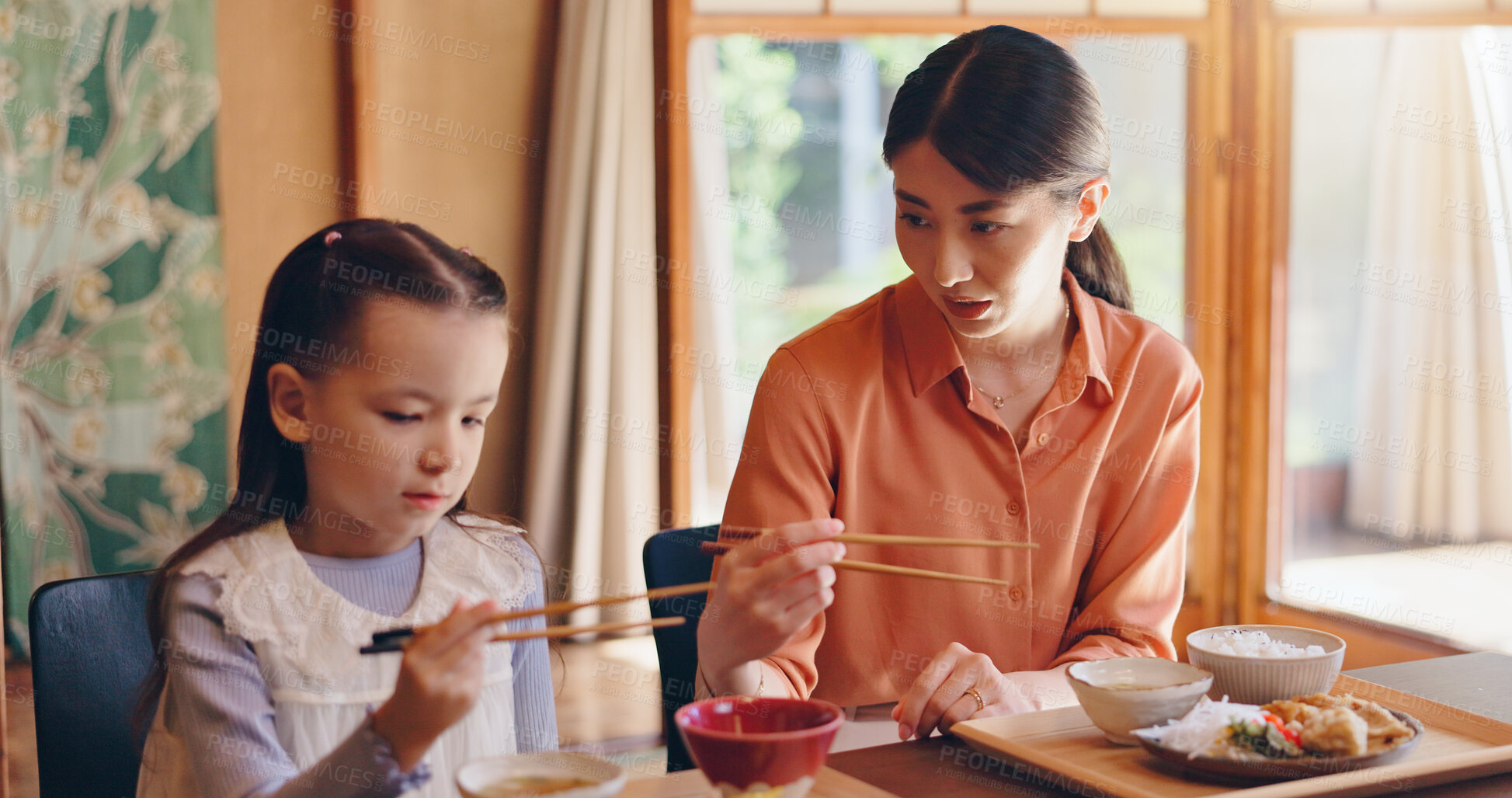 Buy stock photo Mom, girl and chopsticks at lunch, home or teaching for food, eating or bonding for love in dining room. People, mother and daughter family house for meal, diet or nutrition with learning in Japan