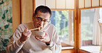 Asian man, eating and food with chopsticks for healthy meal, snack or delicious noodles at home. Japan, male person or bite with bowl or utensils for dining tradition, culture or heritage at house