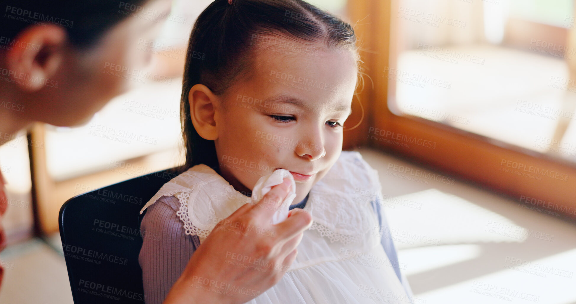 Buy stock photo Wipe, tissue and Asian child with parent in home after eating, breakfast and lunch with napkin for cleaning face. Family, childcare and young girl with mom for hygiene, cleanliness and help in Japan