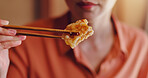 Person, hands or chopsticks with chicken for bite, eating or hungry snack for healthy meal or protein at home. Japan, closeup or food with wooden or bamboo utensils for tradition, culture or heritage