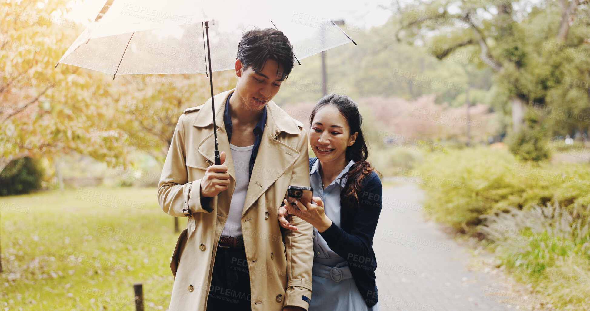 Buy stock photo Umbrella, man and woman in park with phone, checking schedule or online map on morning date. Smartphone, scroll or Japanese couple with mobile app on romantic walk in garden with cover in winter rain