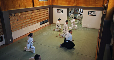 Buy stock photo Dojo, class and Aikido exercise group in gym with wood sword Japanese martial arts and fight in wellness studio. Learning, sport and bamboo weapon with people and strike practice for defence above