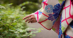 Woman, hands and leaves with kimono, nature and travel for journey and natural sustainability. Japanese person, cultural fashion and plants or bushes with park, garden and outdoor walk for relaxation