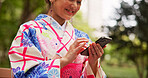 Happy, typing and Asian woman with smartphone, park and communication with contact and fashion designer. Joy, texting and schedule for meeting with client, kimono and message with mobile in Japan