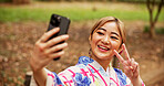 Selfie, smile and woman in nature, peace sign and happy for memory on vacation, travel and kimono. Outdoor, photography and gesture for profile picture, digital and photo for social media in Japan