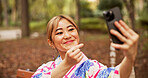 Selfie, travel and woman in nature, gesture and happy for memory on vacation, smile and kimono. Outdoor, photography and profile picture of Asian person, digital and photo for social media in Japan