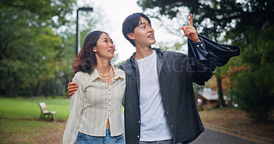 Buy stock photo Happy couple, travel and pointing up outdoor for holiday, sightseeing or hug together. Japanese man, woman and embrace at park on date for romantic connection, love or bonding on vacation for tourism