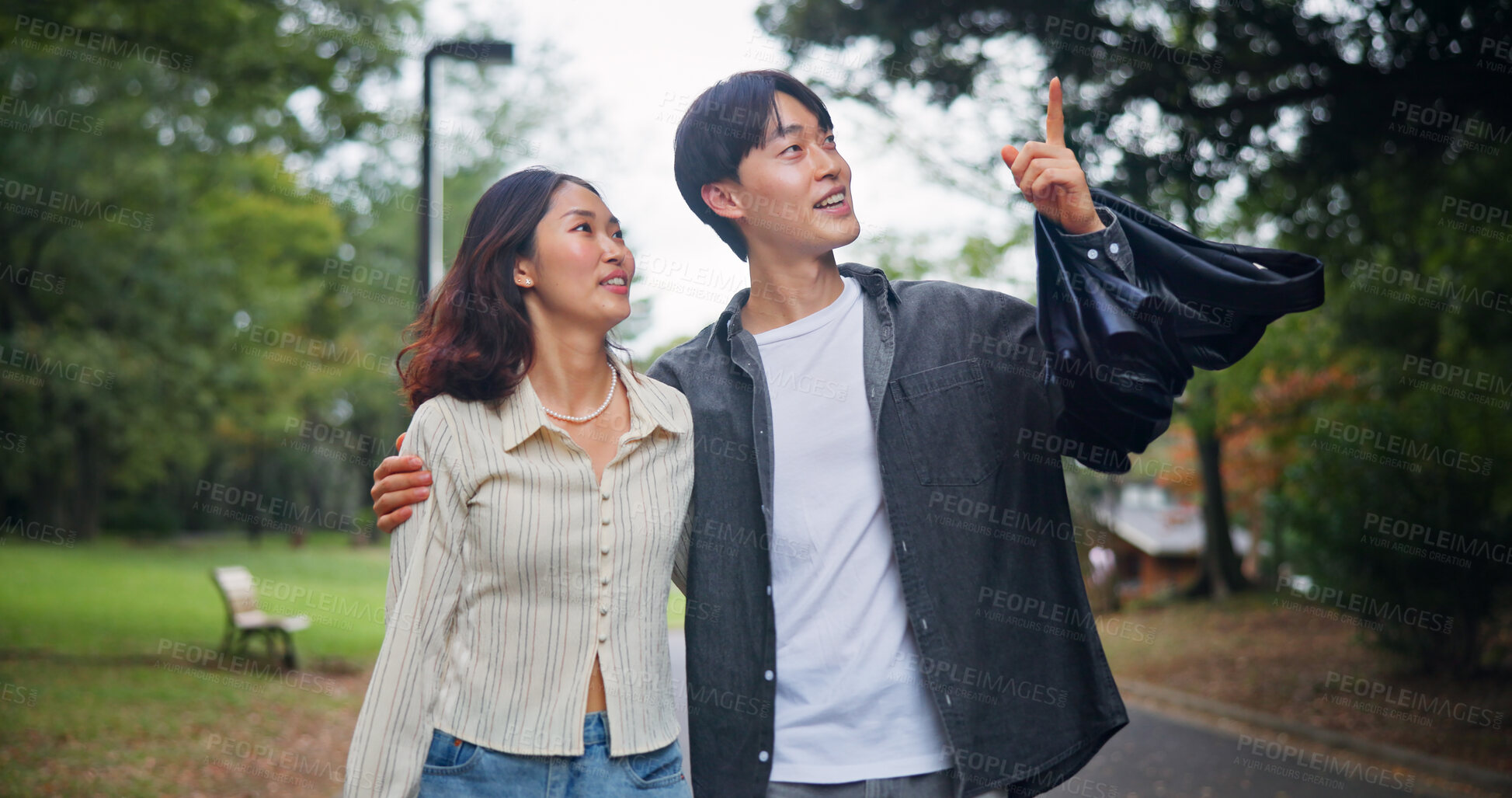 Buy stock photo Happy couple, travel and pointing up outdoor for holiday, sightseeing or hug together. Japanese man, woman and embrace at park on date for romantic connection, love or bonding on vacation for tourism