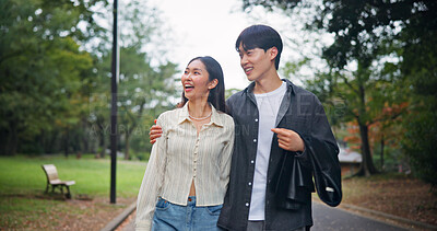 Buy stock photo Asian couple, hug and laughing at park for travel, pointing or sightseeing together on holiday. Japanese man, woman and embrace outdoor on date for romantic connection, love or funny joke on vacation