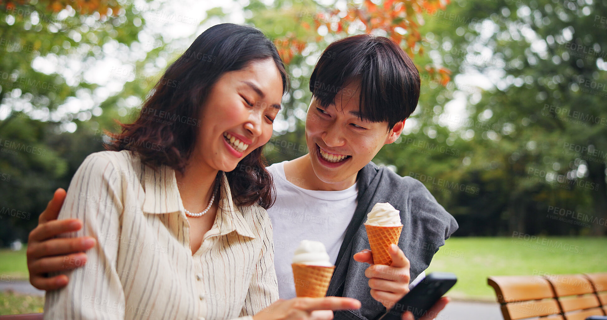 Buy stock photo Couple, phone or happy in park with ice cream, bonding or funny social media in Tokyo. Japanese people, laugh or outdoor with mobile for relationship development, comedy meme or dessert snack on date