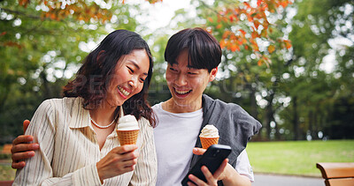 Buy stock photo Couple, mobile or happy in park with ice cream, bonding or funny social media in Tokyo. Japanese people, laugh or outdoor with phone for relationship development, comedy meme or dessert snack on date