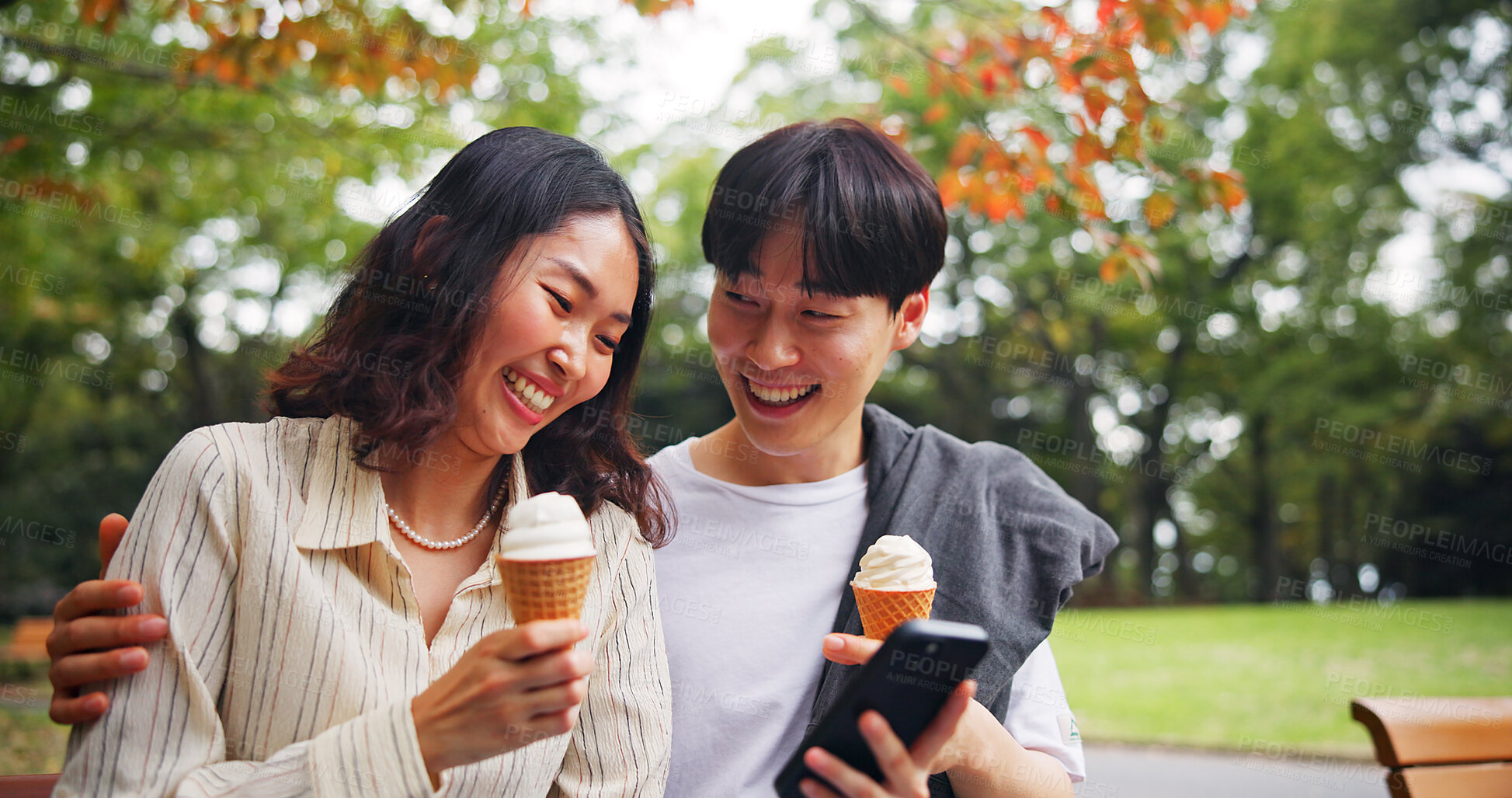 Buy stock photo Couple, mobile or happy in park with ice cream, bonding or funny social media in Tokyo. Japanese people, laugh or outdoor with phone for relationship development, comedy meme or dessert snack on date
