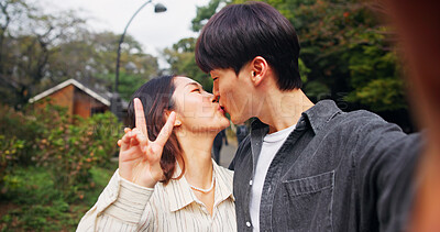 Buy stock photo Kiss, love and selfie of couple outdoor on date for photography, peace sign and care together in Japan. Picture, man and woman with v hand gesture, romantic connection and memory on valentines day