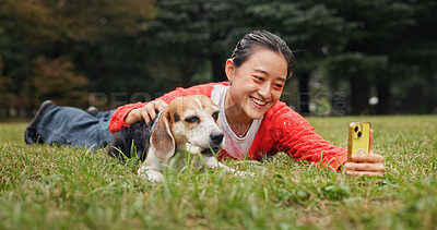 Buy stock photo Selfie, outdoor and woman relaxing with dog for memory, social media or online post in woods. Happy, bonding and Japanese female person on grass with beagle puppy for photography picture in nature.