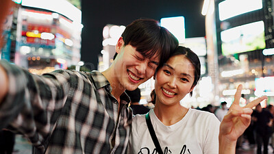 Buy stock photo City, peace sign and selfie at night with couple in Japan together for bonding, love or tourism. Emoji, photograph and smile of happy Japanese woman with man on street for holiday, travel or vacation
